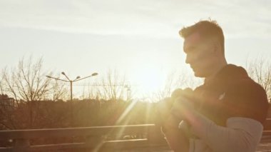 Genç ve zinde bir adam dışarıda akşam antrenmanı yapıyor. Şehir günbatımı geçmişi. Spor ve spor kavramları.