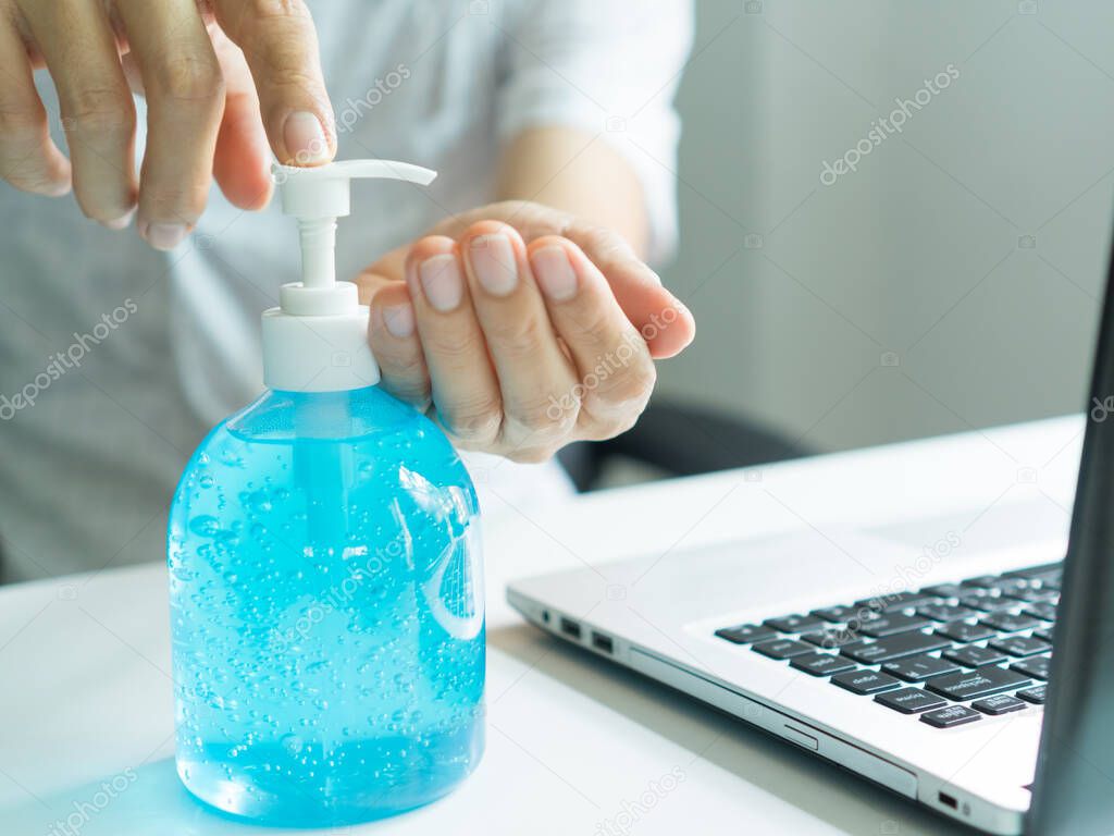 The hand of a middle-aged man who is using alcohol gel to clean his hands before and after using a laptop.