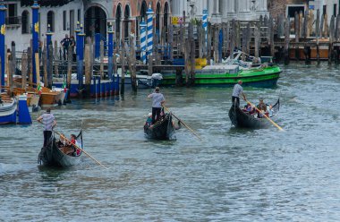 Venedik 'te (Venezia), İtalya' da üç gondolcu gondollarına biner.