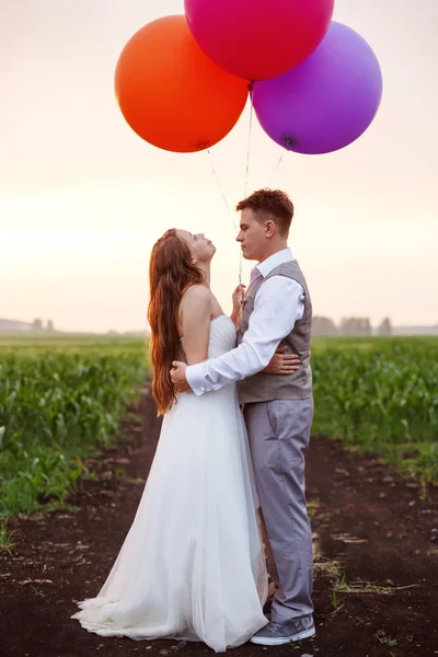 Свадебная пара стоящая с воздушными шарами на поле — стоковое фото