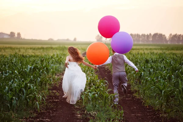 Hochzeitspaar auf Feld mit Luftballons — Stockfoto