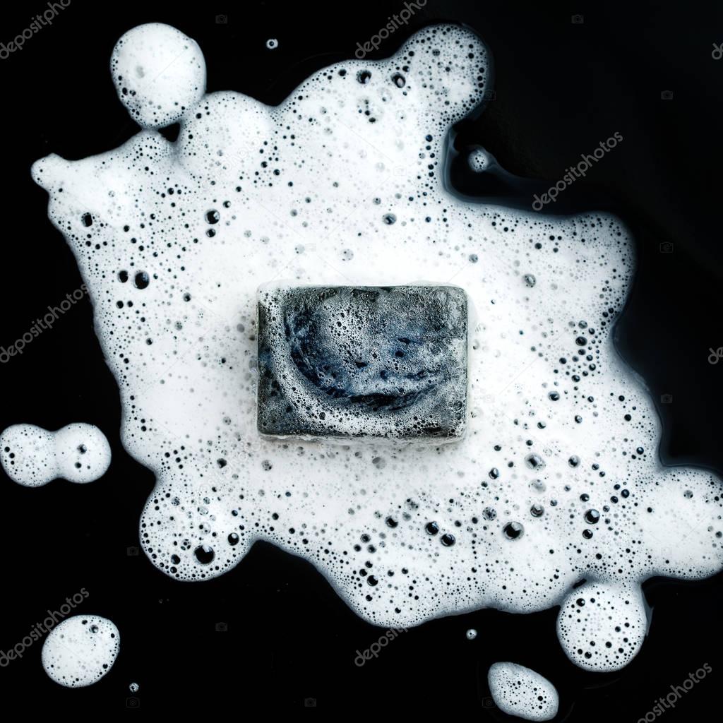 Black coal bar of soap in foam 