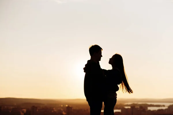 Casal abraçando em um telhado ao pôr do sol — Fotografia de Stock