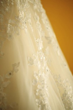 Sarı arka planda gelinliğin yakın plan detayları, seçici odak