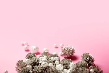 Gümüş kozalaklı Noel kompozisyonu ve parlak pembe arka planda küçük parlak toplar, kopyalama alanı