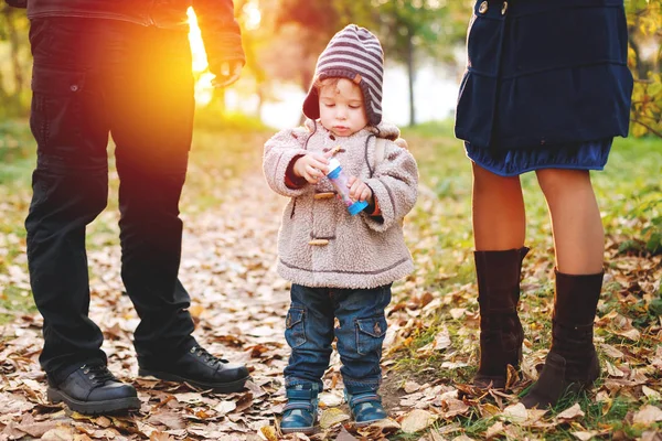 Lindo niño de dos años en ropa de abrigo de pie entre sus padres — Foto de Stock