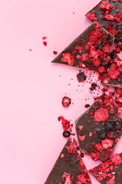Kırık siyah çikolata parçaları ve kurutulmuş kırmızı böğürtlen. — Stok fotoğraf