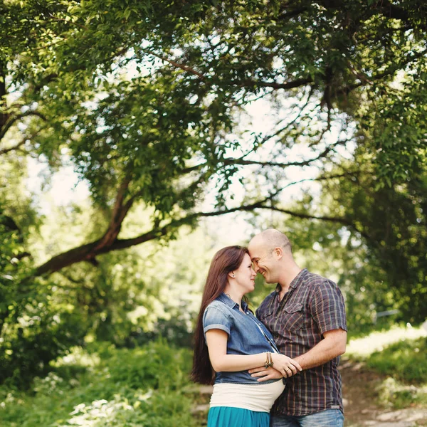 Man en zwangere vrouw, omhelzing in het park buiten — Stockfoto