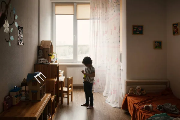 Little gril standing in front of window in her bedroom — Stock Photo, Image