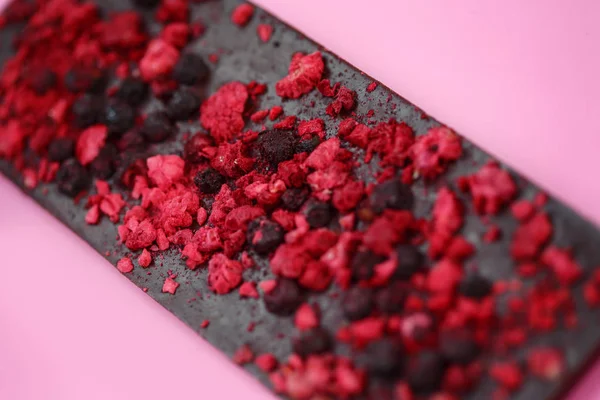 Chocolate preto de baixa caloria com bagas vermelhas secas em fundo rosa brilhante — Fotografia de Stock
