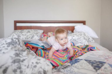 Cute infant girl with light hair lying on her tummy in parent`s 