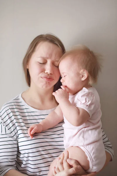 Молодая привлекательная мать держит своего маленького плачущего ребенка на своей ха — стоковое фото