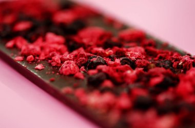 Koyu düşük kalorili çikolata, açık pembe üzerinde kurutulmuş kırmızı böğürtlen.