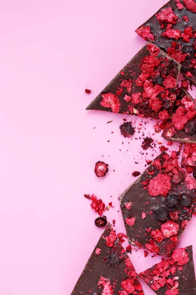 Pièces de barres de chocolat cassées avec des baies rouges séchées dispersées et — Photo