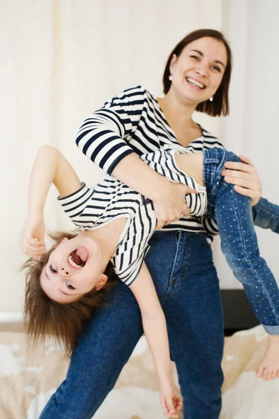 Young happy mother having fun with her cute little baby holding her upside down, playing and laughing, active games at home — Stock Photo, Image