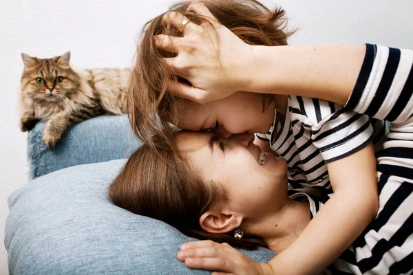 Primer plano de abrazar a la madre y a la hija cariñosas en la misma ropa, besar a la madre, reír y acariciar el cabello del niño — Foto de Stock