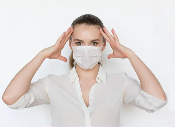 COVID-19 Pandemic Coronavirus Žena s obličejovou maskou na ochranu proti šíření viru onemocnění SARS-CoV-2. Dívka v hrůze drží jeho ruce za jeho hlavu na bílém pozadí — Stock fotografie