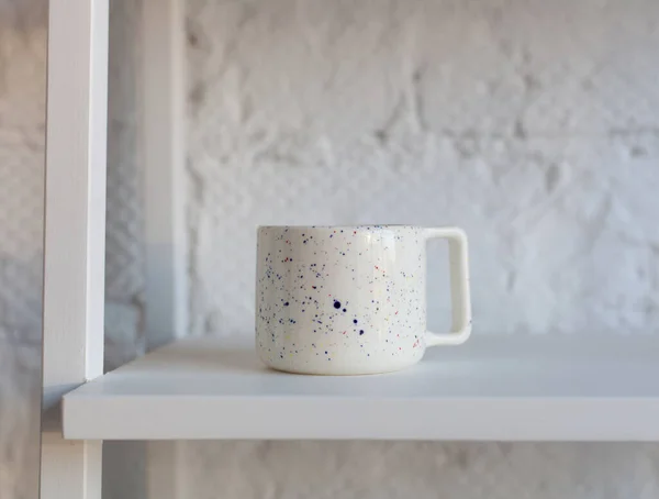 白い本棚に美しい手作りのセラミックカップ ロイヤリティフリーのストック画像