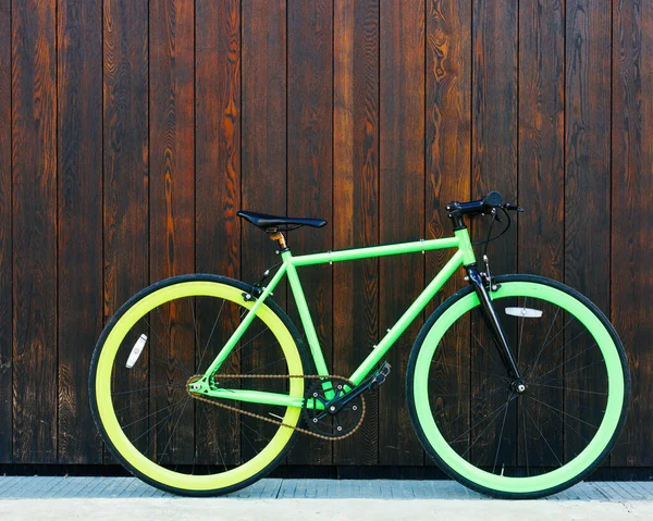 Bright green Fixed Gear beautiful vintage bicycle stands in a black wooden wall Stock Photo
