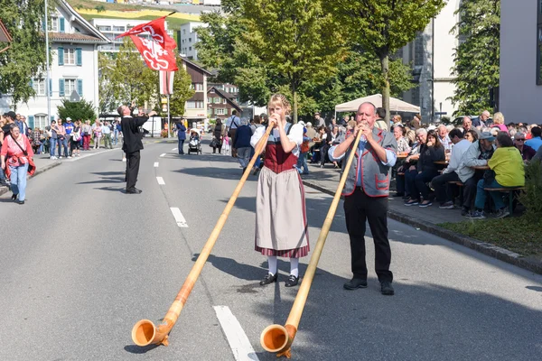 Geleneksel giyim eşyası ve alphorn oynayan insanlar  