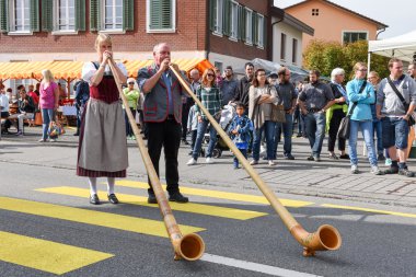 Geleneksel giyim eşyası ve alphorn oynayan insanlar  