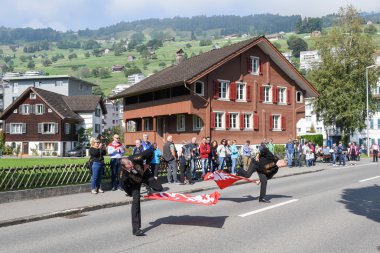 Geleneksel giyim eşyası ve bayraklar sallayarak insanlar 
