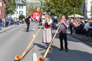 Geleneksel giyim eşyası ve alphorn oynayan insanlar  