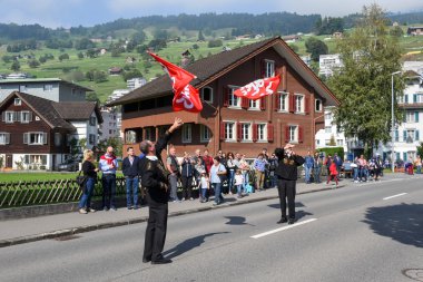 Geleneksel giyim eşyası ve bayraklar sallayarak insanlar 