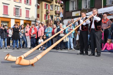 Geleneksel giyim eşyası ve alphorn oynayan insanlar  