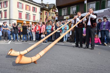 Geleneksel giyim eşyası ve alphorn oynayan insanlar  