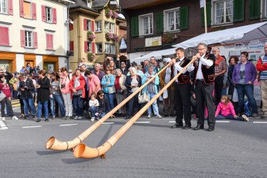 Geleneksel giyim eşyası ve alphorn oynayan insanlar 