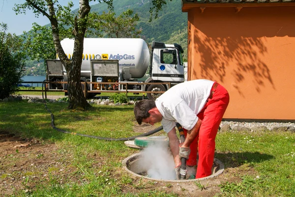 Travailleur faisant l'approvisionnement en gaz sur un réservoir dans le jardin — Photo
