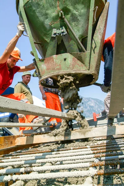 Des travailleurs de la rue versent du ciment dans une construction routière — Photo