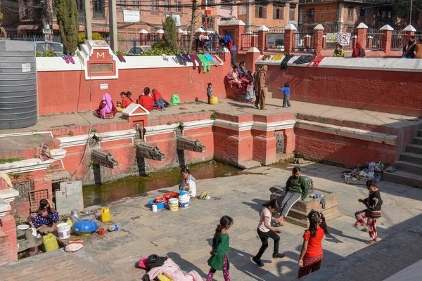 Las mujeres lavan la ropa y las hijas jugando en la fuente de Pata —  Fotos de Stock