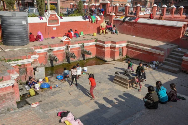 Las mujeres lavan la ropa y las hijas jugando en la fuente de Pata —  Fotos de Stock