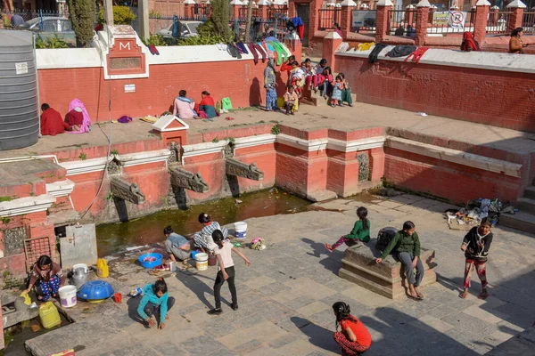 Las mujeres lavan la ropa y las hijas jugando en la fuente de Pata —  Fotos de Stock