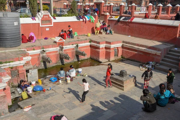 Kvinnor tvättar kläder och döttrar leker vid fontänen i Pata — Stockfoto