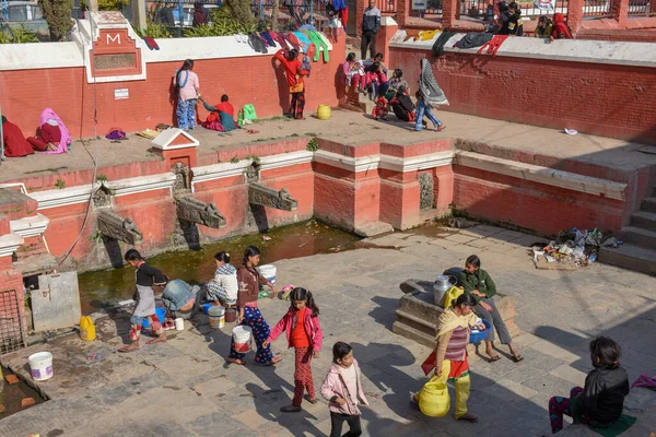 Las mujeres lavan la ropa y las hijas jugando en la fuente de Pata —  Fotos de Stock