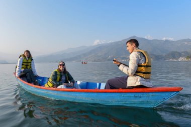 Pokhara, Nepal - 12 Ocak 2020: Nepal 'deki Pokhara gölünde insanlar bir kanoda hareket ediyor