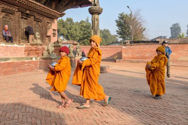 Bhaktapur, Nepal - 28 Ocak 2020: Nepal 'deki Bhaktapur' da sabah sadakalarında yürüyen genç Budist rahipler