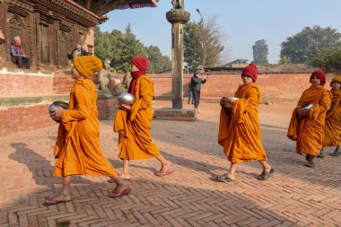 Bhaktapur, Nepal - 28 Ocak 2020: Nepal 'deki Bhaktapur' da sabah sadakalarında yürüyen genç Budist rahipler