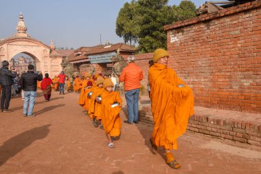 Bhaktapur, Nepal - 28 Ocak 2020: Nepal 'deki Bhaktapur' da sabah sadakalarında yürüyen genç Budist rahipler