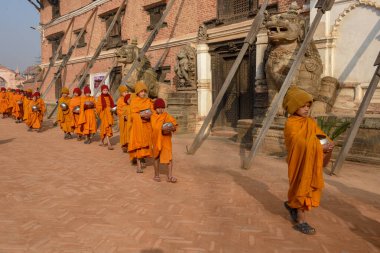 Bhaktapur, Nepal - 28 Ocak 2020: Nepal 'deki Bhaktapur' da sabah sadakalarında yürüyen genç Budist rahipler