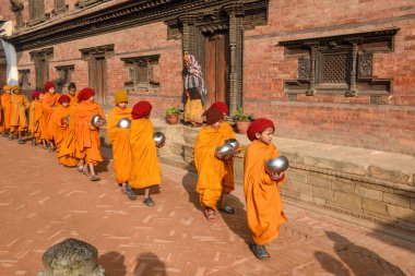 Bhaktapur, Nepal - 28 Ocak 2020: Nepal 'deki Bhaktapur' da sabah sadakalarında yürüyen genç Budist rahipler