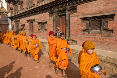 Bhaktapur, Nepal - 28 Ocak 2020: Nepal 'deki Bhaktapur' da sabah sadakalarında yürüyen genç Budist rahipler