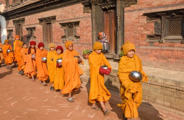 Bhaktapur, Nepal - 28 Ocak 2020: Nepal 'deki Bhaktapur' da sabah sadakalarında yürüyen genç Budist rahipler