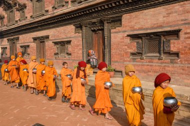 Bhaktapur, Nepal - 28 Ocak 2020: Nepal 'deki Bhaktapur' da sabah sadakalarında yürüyen genç Budist rahipler