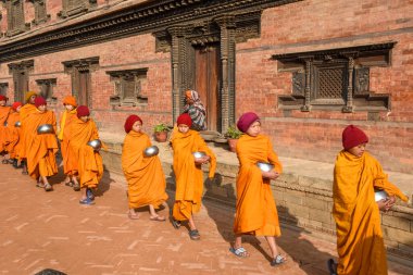 Bhaktapur, Nepal - 28 Ocak 2020: Nepal 'deki Bhaktapur' da sabah sadakalarında yürüyen genç Budist rahipler