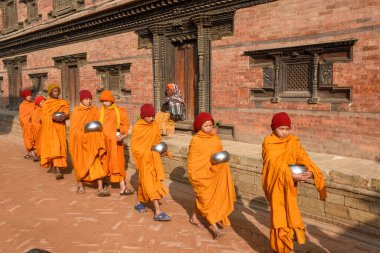 Bhaktapur, Nepal - 28 Ocak 2020: Nepal 'deki Bhaktapur' da sabah sadakalarında yürüyen genç Budist rahipler