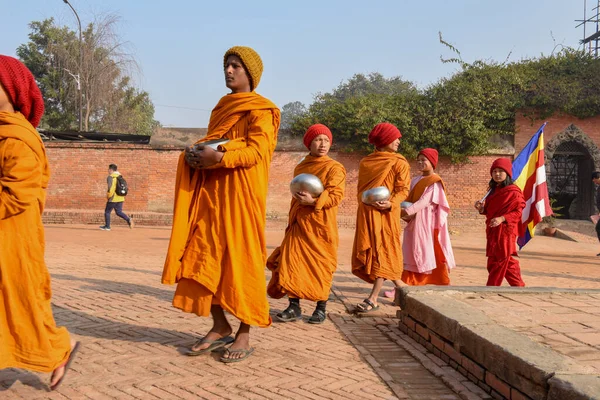 Bhaktapur, Nepal - 28 Ocak 2020: Nepal 'deki Bhaktapur' da sabah sadakalarında yürüyen genç Budist rahipler
